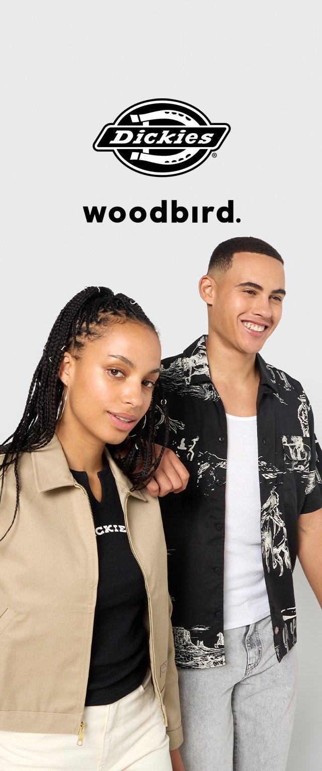 Khaki jasje met een rits en zwart grafisch shirt; model draagt een zwart t-shirt en lichte jeans. Logo boven: Dickies woodbird.