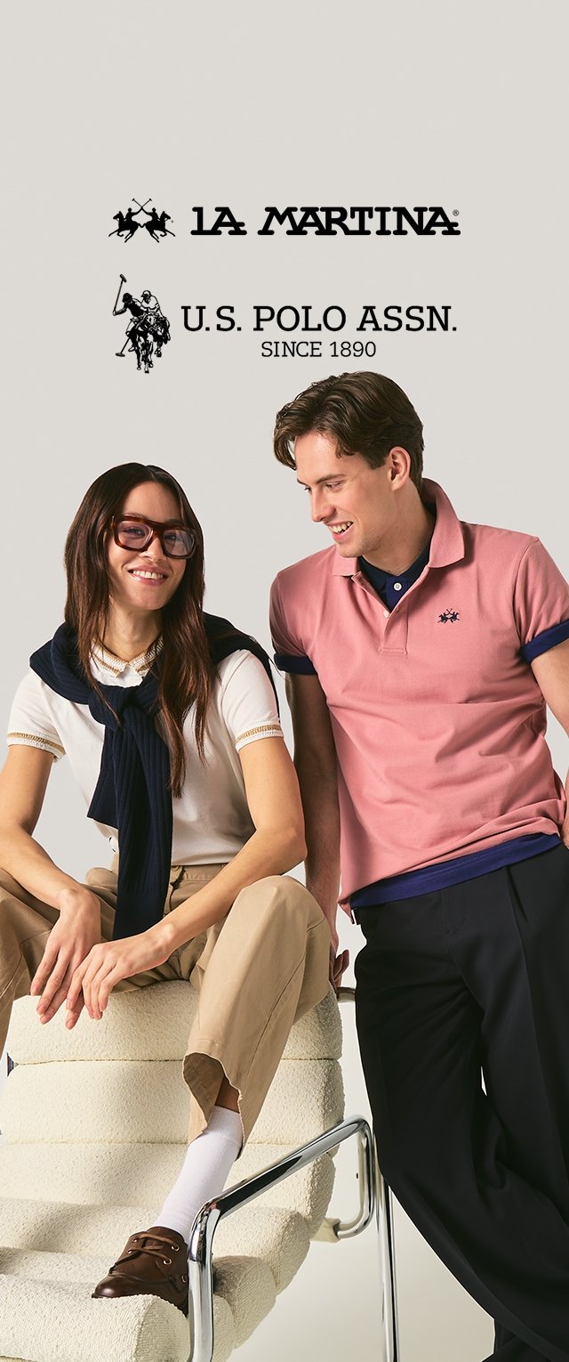 Homme souriant en polo rose et femme en chemise blanche avec un pull marine discutent, assis sur et à côté d'une chaise blanche moderne.