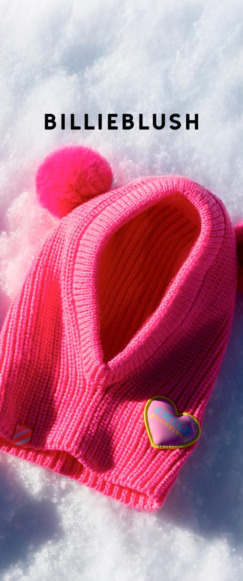 Kirkkaan vaaleanpunainen neulottu balaclava tupsuilla ja sydämenmuotoisella "Smile Billieblush"-merkillä lumella.