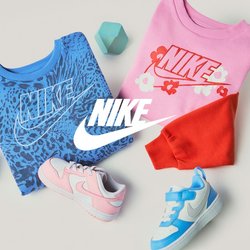 Složené modré a růžové mikiny Nike s logem, dvě dětské tenisky v růžové a modré barvě, červené a modré geometrické bloky na béžovém pozadí.
