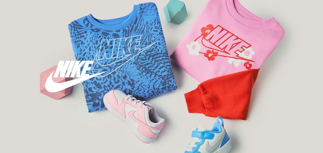 Složené modré a růžové mikiny Nike s logem, dvě dětské tenisky v růžové a modré barvě, červené a modré geometrické bloky na béžovém pozadí.