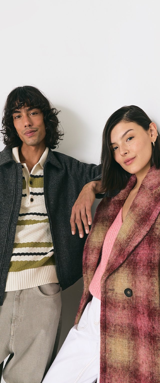 Dos modelos lucen atuendos en capas: un abrigo de lana oscuro, un suéter a rayas y pantalones claros; una blusa de canalé rosa bajo un abrigo texturizado rosa-marrón.