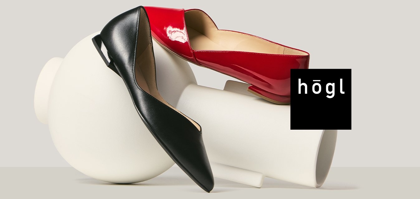 Dva vysoké podpatky, jeden červený a jeden černý, odpočívající na a kolem bílých válcových a kulatých abstraktních tvarů.