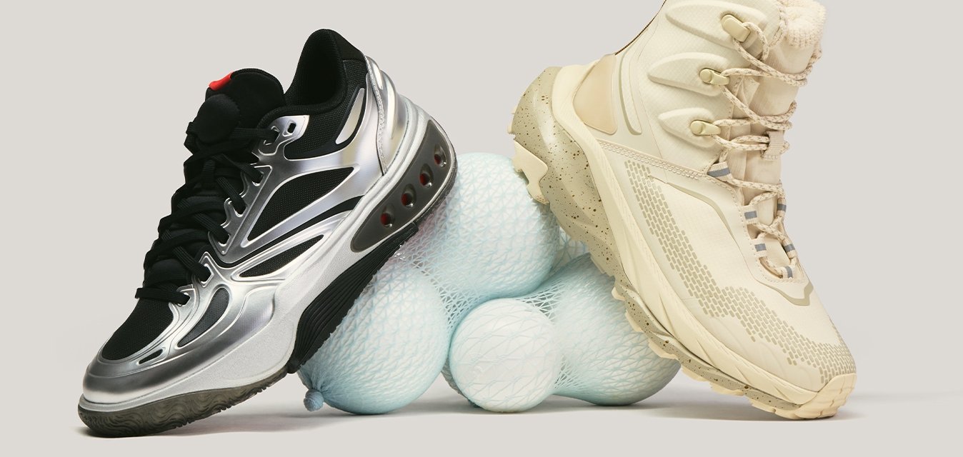 Černá a stříbrná atletická bota a béžová turistická bota spočívající na hromádce bílých golfových míčků na světlém pozadí.