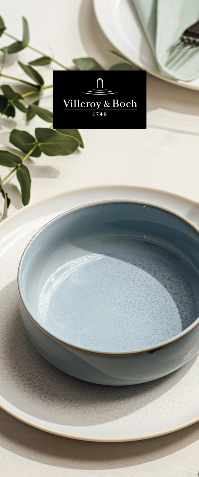 Ceramiczna miska w delikatnym niebieskim kolorze z teksturowanym wykończeniem, obramowana złotem, umieszczona na jasnej talerzu w wzory o gładkiej powierzchni.