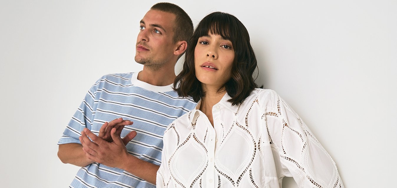 Pruhované modro-bílé tričko v kombinaci s béžovými kalhotami, vedle něj bílé krajkové tričko s diamantovými výřezy a pruhované kalhoty. Jednoduché pozadí.