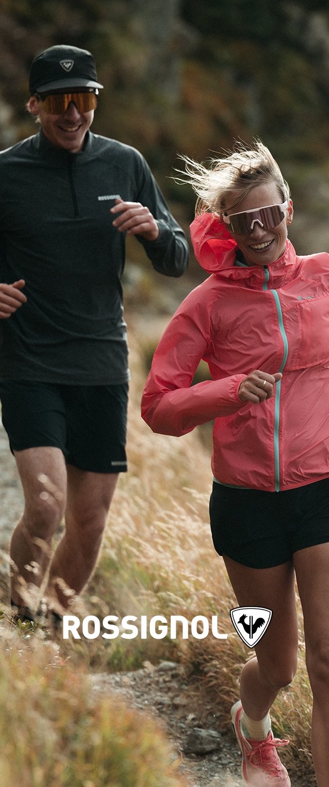Two runners on a trail: one in a black long-sleeve shirt, the other in a bright pink jacket. Both wear sunglasses and shorts.