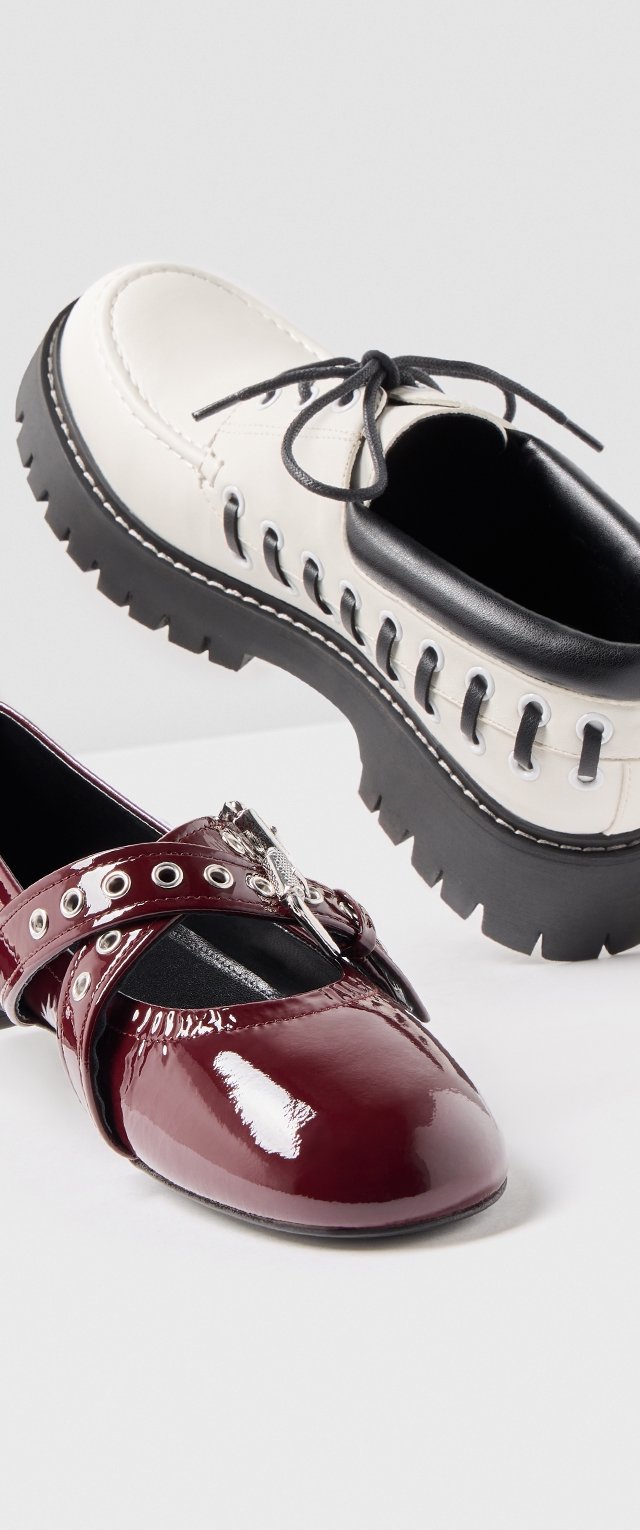 Deux paires de chaussures : l'une est en cuir noir et blanc avec une semelle épaisse et des lacets, l'autre est en cuir verni bordeaux avec des œillets et une boucle décorative.