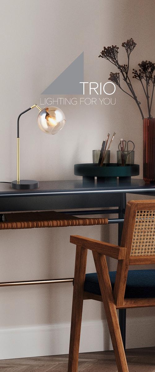 Escritorio moderno con una lámpara de globo de vidrio iluminada, silla de madera con asiento tejido, herramientas en recipientes y ramas secas en un jarrón alto.