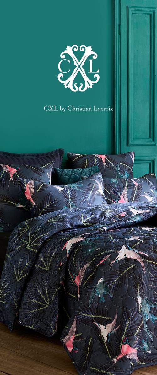 Juego de cama acolchado de color azul oscuro con patrones de pájaros y hojas coloridos, acompañado de múltiples cojines decorativos a juego.