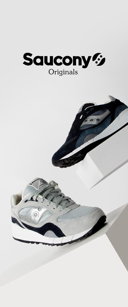 Baskets Saucony en gris et bleu marine. Comprennent des matériaux en suède et en mesh, un design à bout rond et des accents ton sur ton, exposées sur un piédestal blanc.