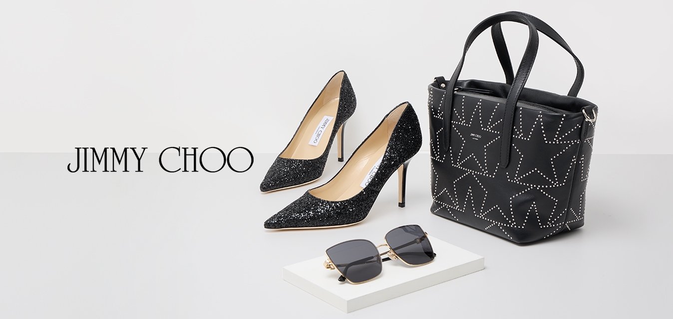 Černé vysoké podpatky se třpytkami, černá kabelka se cvočky a hvězdnými vzory a nadměrné černé sluneční brýle na bílém povrchu.