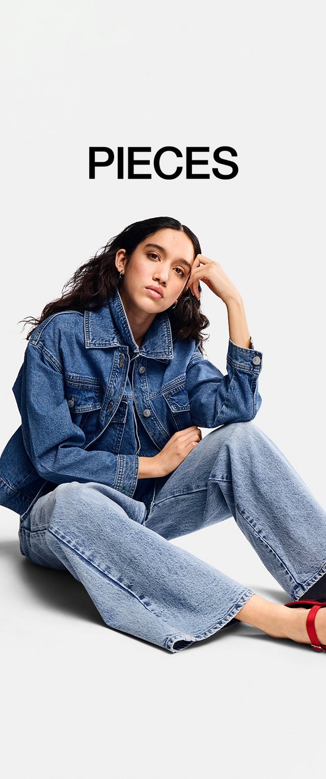 Veste en jean bleu foncé avec fermeture à boutons et deux poches poitrine, associée à un jean léger à jambes larges bleu clair. Sandales à talons rouges.