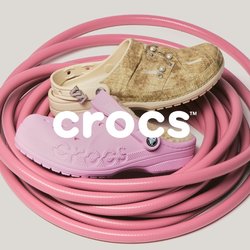 Zavinutá růžová zahradní hadice s třemi opotřebovanými gumovými botami v barvách světlehnědá, béžová a světle růžová položenými na ní na jednobarevném pozadí.