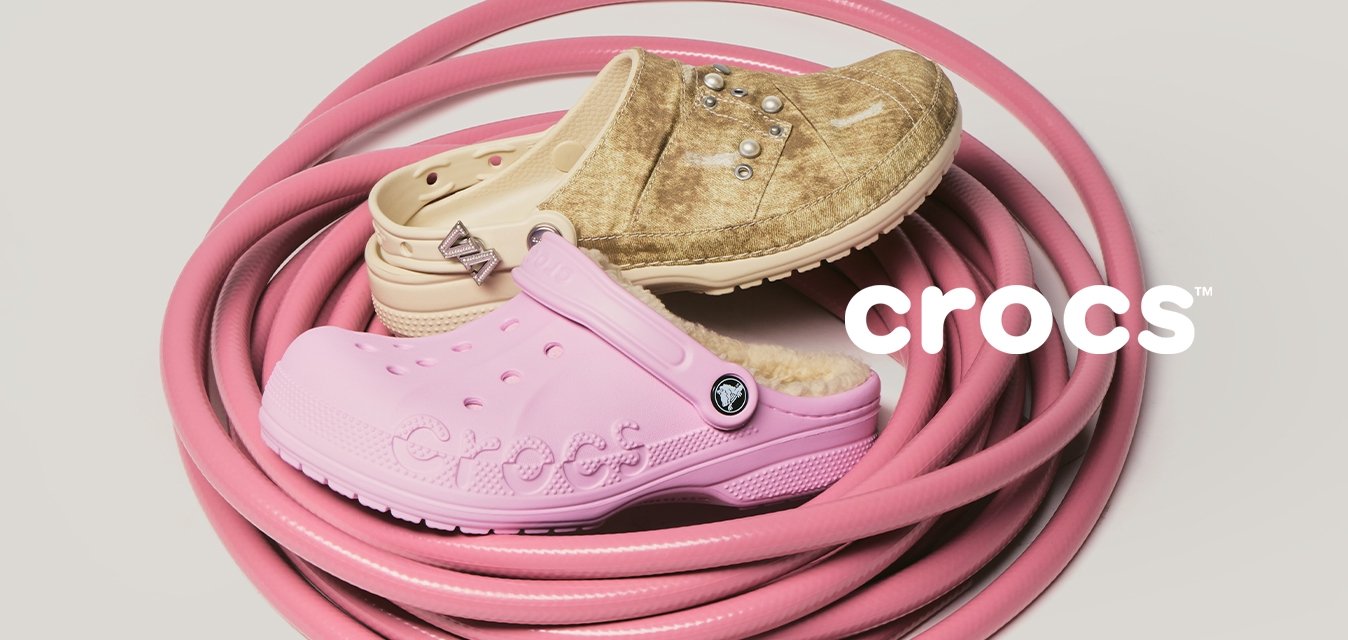 Zavinutá růžová zahradní hadice s třemi opotřebovanými gumovými botami v barvách světlehnědá, béžová a světle růžová položenými na ní na jednobarevném pozadí.