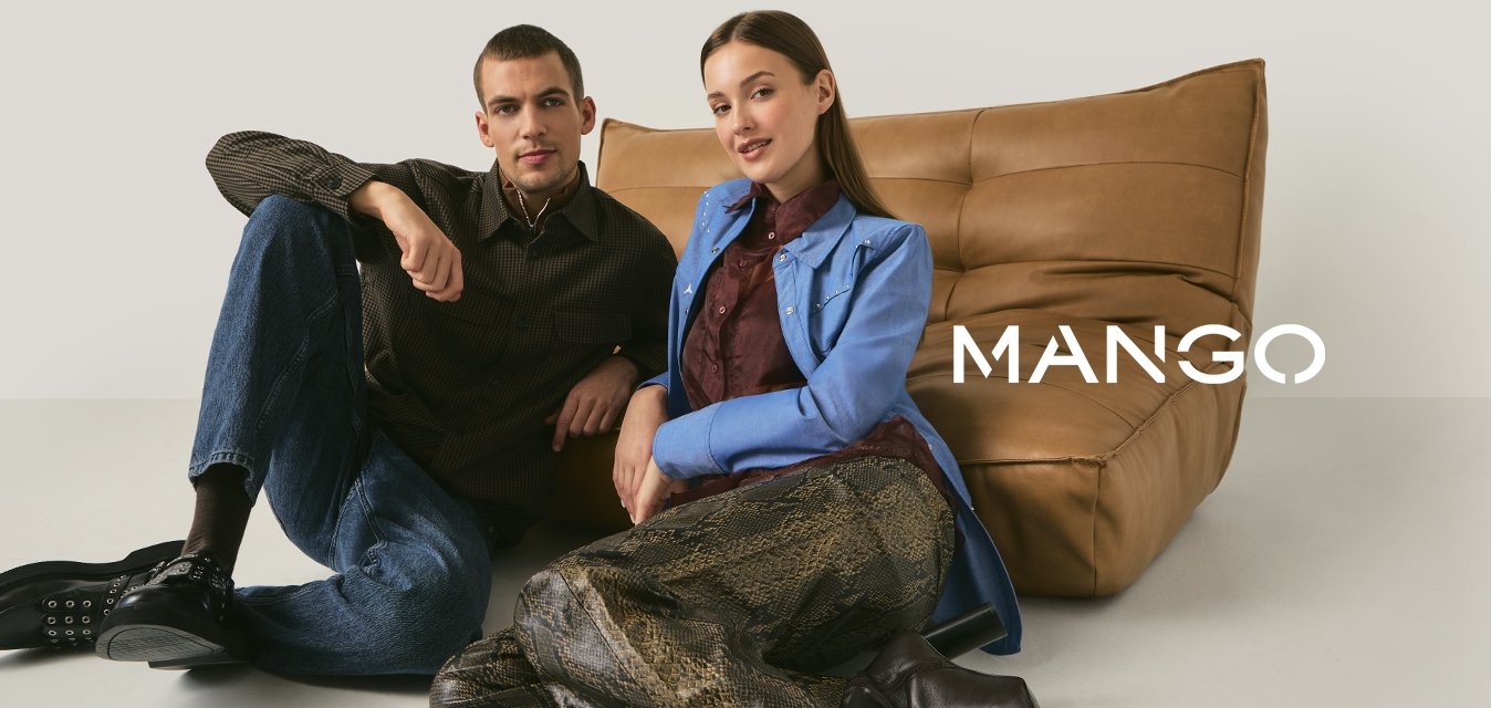 Mladý muž a žena sedící na podlaze opření o hnědou koženou pohovku, oblečeni v neformálním stylovém oblečení na jednobarevném pozadí.