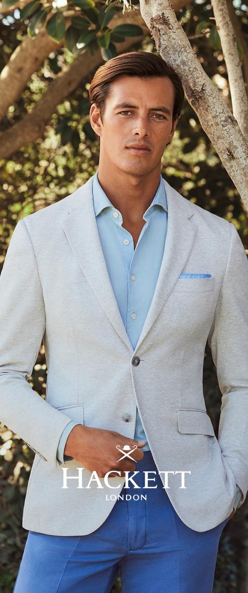 Blazer gris clair avec un bouton, porté sur une chemise bleu clair, complété par un mouchoir de poche à motifs bleus. Présentant une coupe ajustée.