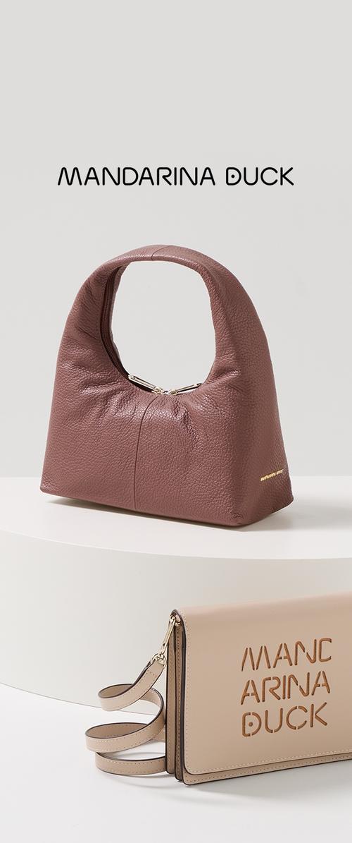 Bolso de cuero marrón texturizado con un asa curva, que cuenta con un cierre de cremallera. Incluye un bolso de mano beige con logotipo recortado y correa desmontable.