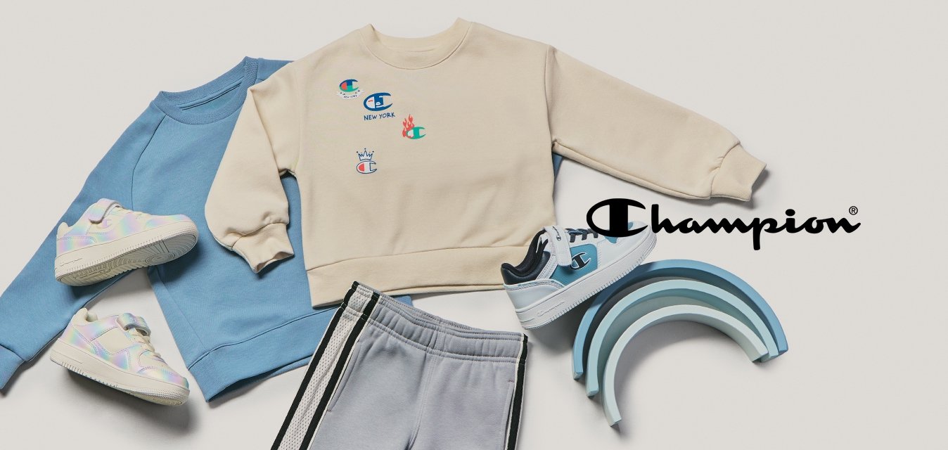 Dvě dětská mikiny, šedé tepláky, tři páry tenisek a hromada modrých dřevěných hraček ve tvaru duhy na béžovém pozadí.