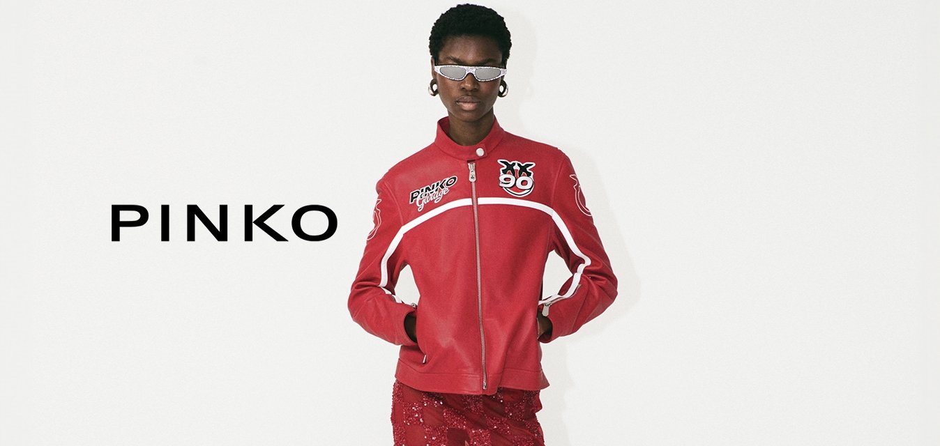 Červená bunda se zipem a logem, kombinovaná s červenou krajkovou midi sukni s kostkovaným vzorem a bílými vysokými podpatky.