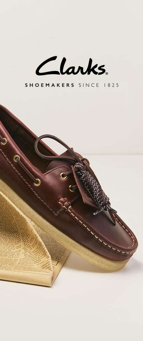 Brauner Clarks Bootsschuh aus Leder mit beiger Sohle auf gefalteter Zeitung, Clarks-Logo und Text "Shoemakers since 1825" über dem Schuh.