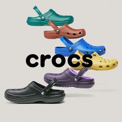Šest barevných Crocs obuvi v černé, fialové, žluté, modré, červené a zelené barvě, uspořádaných ve vertikálně staggerované formaci na světlém pozadí.