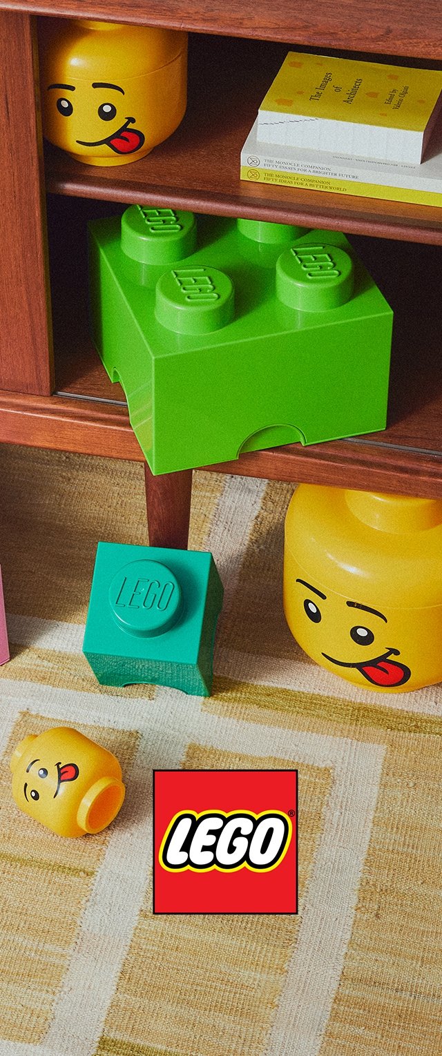 Green LEGO storage box with four raised dots, a turquoise box with LEGO logo, and two yellow boxes with smiley faces on a wooden shelf.