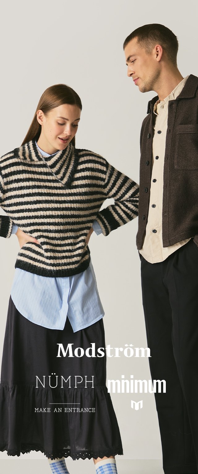 Gestreifter Strickpullover in Creme und Schwarz, darüber ein hellblaues Hemd und ein schwarzer Rock mit Rüsche. Mann in einer dunkelbraunen Jacke mit Knöpfen.