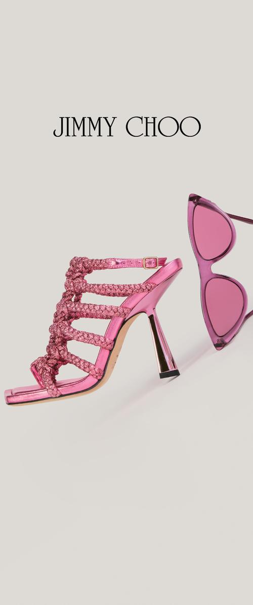 Sandale rose à talon haut avec brides tressées à côté de lunettes de soleil cat-eye assorties, les deux sur un fond uni sous le logo Jimmy Choo.