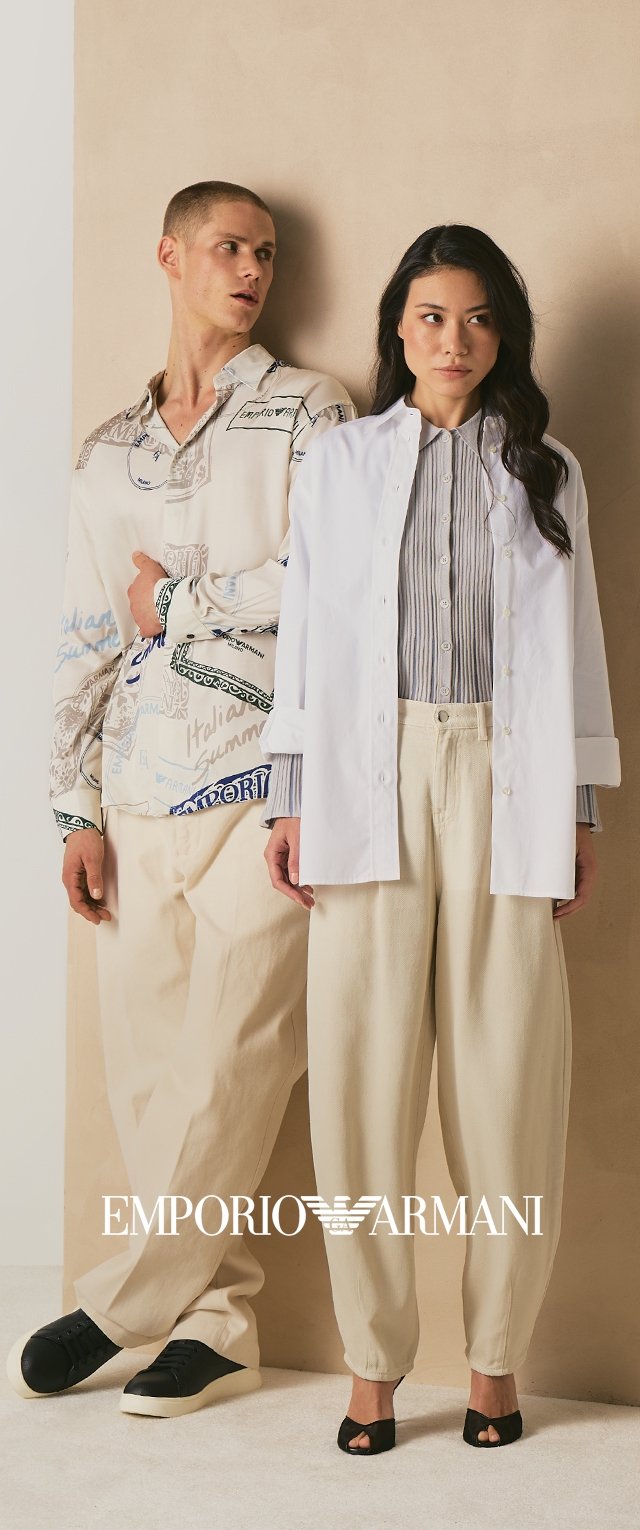 Man in patterned button-up shirt and cream pants with black sneakers, woman in white open jacket, striped shirt, cream pants, and black heels.