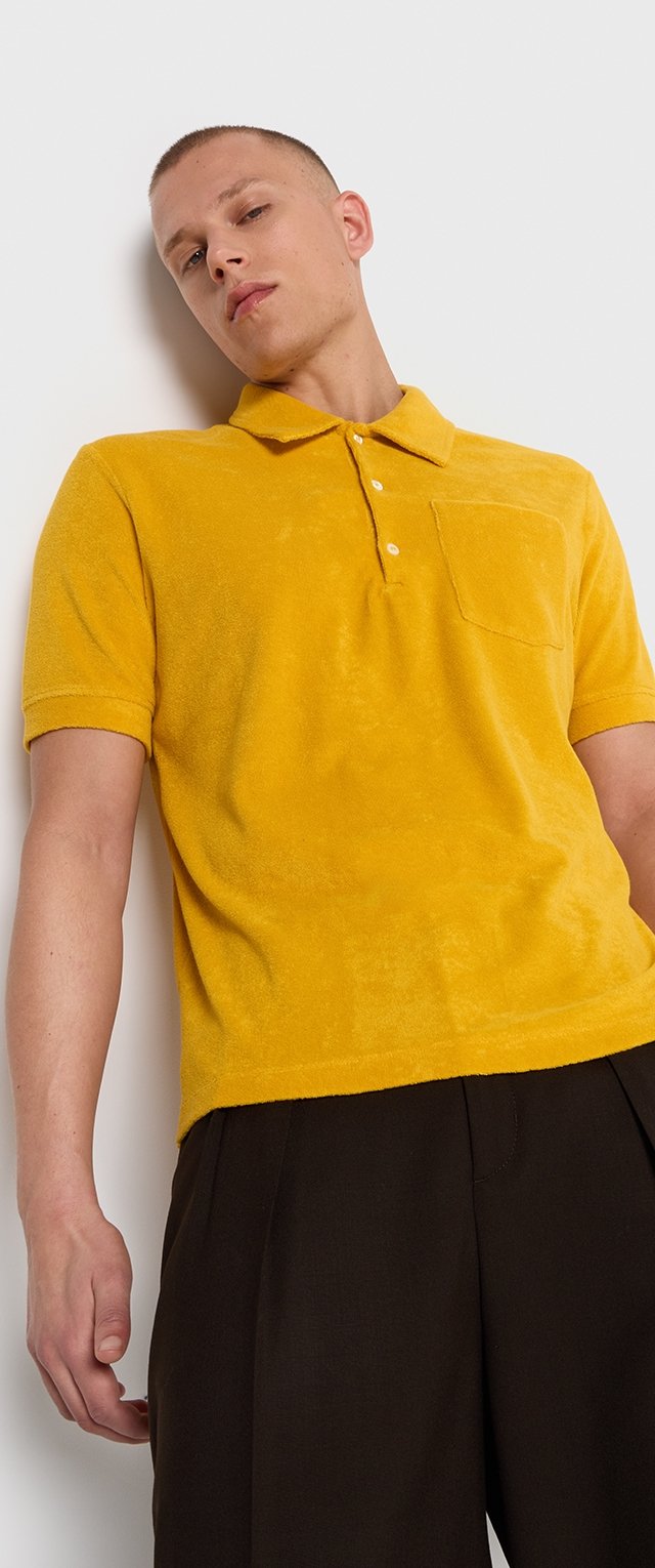 Camisa polo de manga corta en vibrante tela de rizo amarilla, con un cuello clásico, tapeta de tres botones y un bolsillo en el pecho.