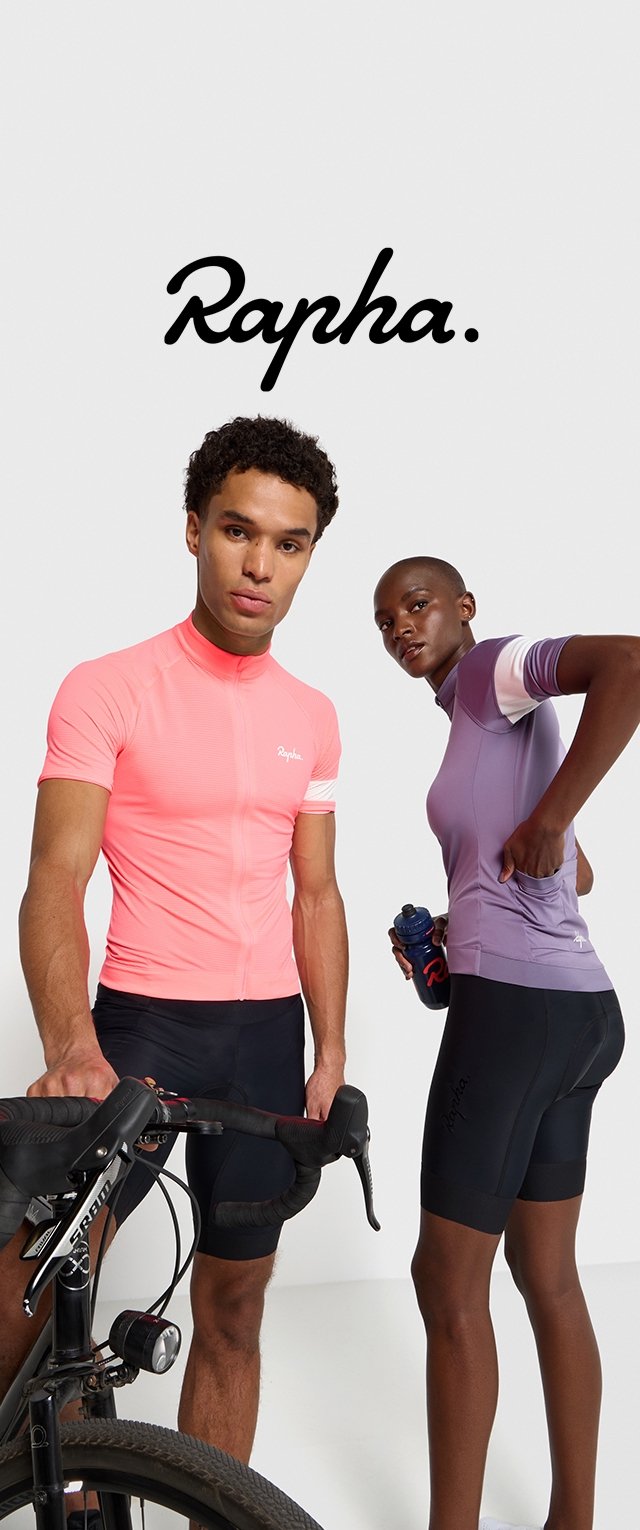 Jersey de ciclismo rosa de manga corta con tejido texturizado, pantalones cortos de ciclismo negros, jersey morado con rayas blancas y una bicicleta en primer plano.