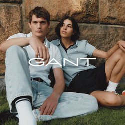 Dva jednotlivci sedí u kamenné zdi. Muž má na sobě bílé polo tričko a světlé modré džíny; žena má na sobě světlé modré polo tričko a černé šortky.