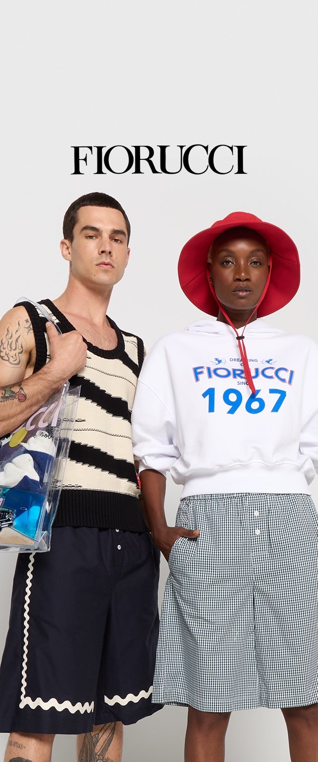Schwarz-weißer gestreifter Strick-Top, dunkelblaue Shorts mit Wellenmuster, weiße Kapuzenjacke mit blauer Schrift, karierte Shorts und ein rotes Bucket Hat.
