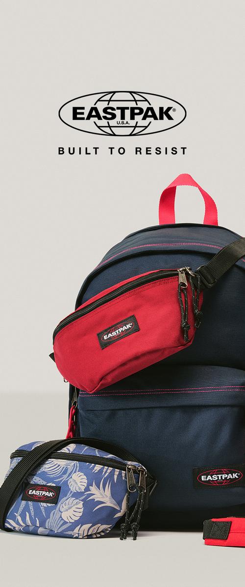 Mörkblå Eastpak-ryggsäck med rött handtag, röda och blå mönstrade magväskor och "Built to Resist" slogan ovanför logotypen.