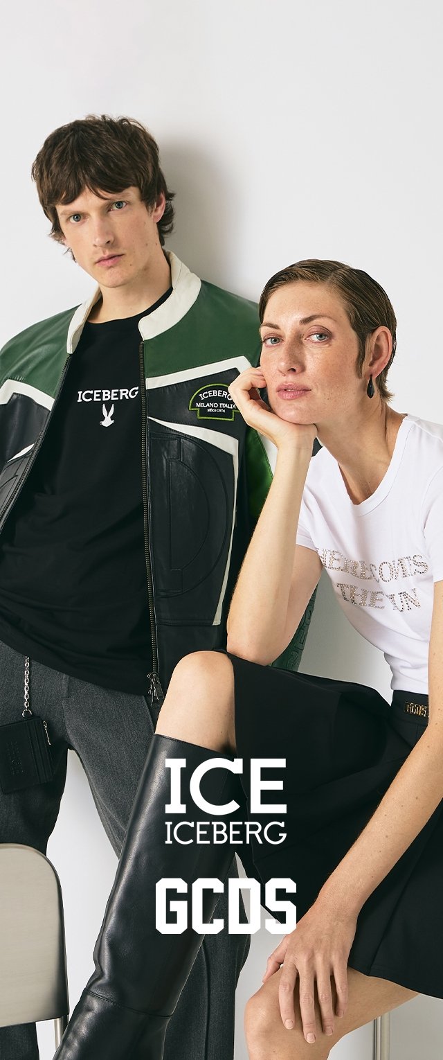 Veste en cuir verte et noire, t-shirt noir avec logo, t-shirt blanc avec texte métallique, jupe noire et bottes noires à hauteur de genou.