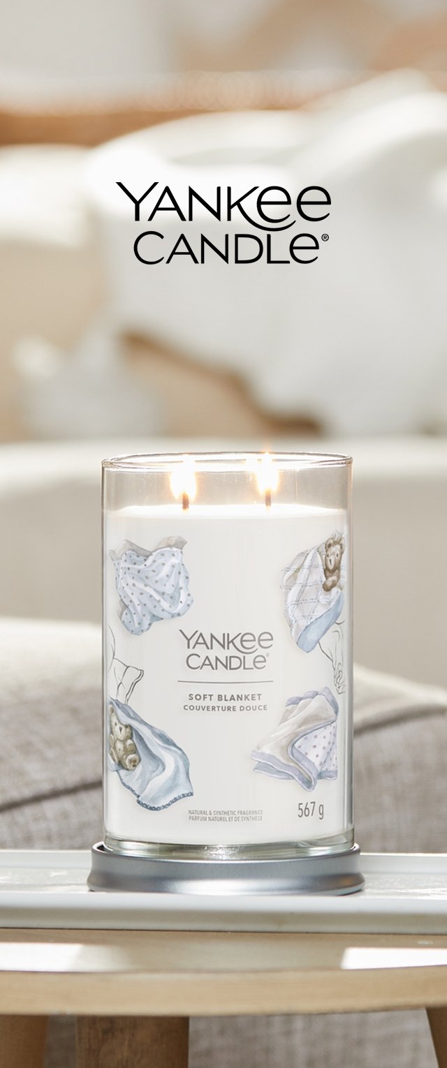 Yankee Candle in een duidelijke glazen pot heeft een wit etiket met illustraties van zachte dekens en een beer, bovenop twee brandende lonten.