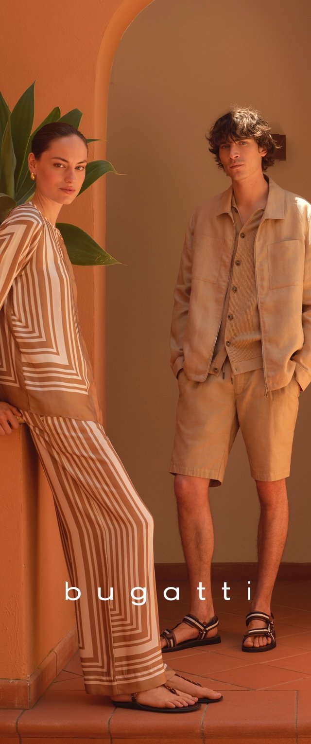 Mujer con conjunto de rayas beige y blanca y hombre con chaqueta beige, pantalones cortos y sandalias posan en un entorno arquitectónico de tonos cálidos con hojas de plantas.
