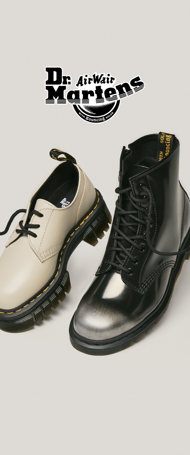 Beige leather lace-up shoe and black patent leather combat boot, both feature thick rubber soles with yellow stitching and branded markings.