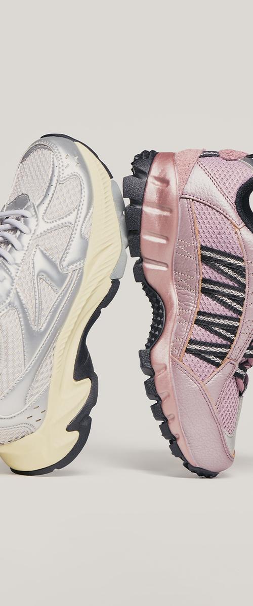 Zilveren mesh sneaker met een gele zool en een roze gestructureerde sneaker met zwarte accenten, beide met opvallende profielpatronen.