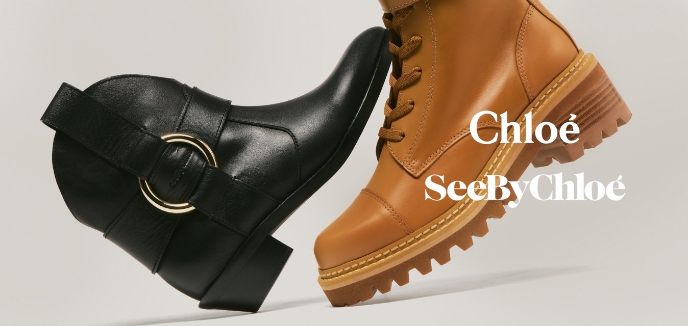 Černá kotníková bota se zlatým kroužkem čelem k béžové šněrovací bojové botě s dvojitými přezkami na béžovém pozadí.