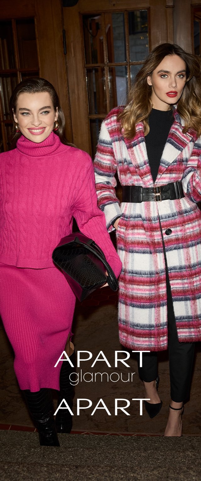 Two women are dressed in vibrant outfits: one in a textured pink sweater and skirt, the other in a plaid coat with a belt, paired with fitted black pants.