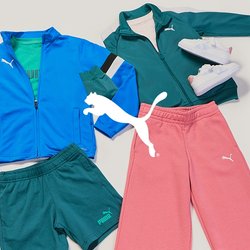 Dva sportovní outfity s logem Puma: modrá bunda, zelené šortky, tenisky; zelená bunda, růžové kalhoty, bílé tenisky, rozložené na bílém povrchu.