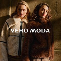 Dvě ženy stojící blízko sebe, oblečené v texturovaných zimních bundách, jedna krémová s černými akcenty, druhá tmavě hnědá, na pozadí stínované zdi.