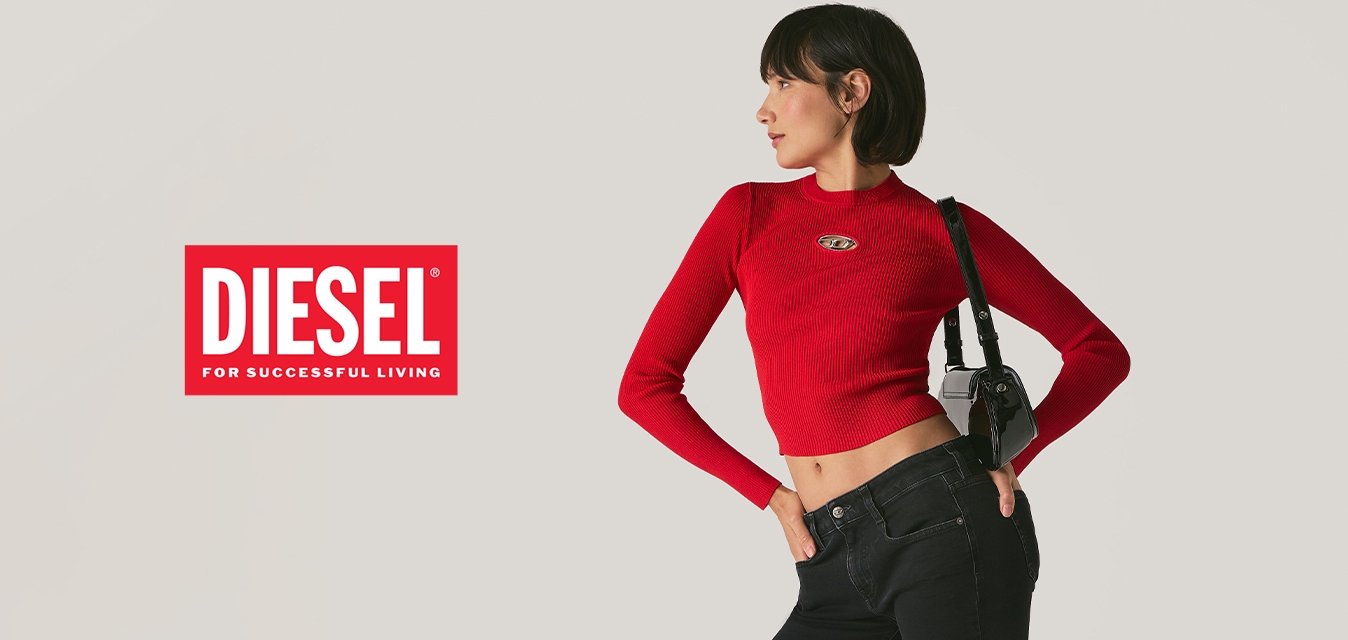 Žena pózující v černých rozšířených džínách, červeném dlouhém topu na břicho, černých sandálech a držící černou kabelku přes rameno na jednolitém pozadí.