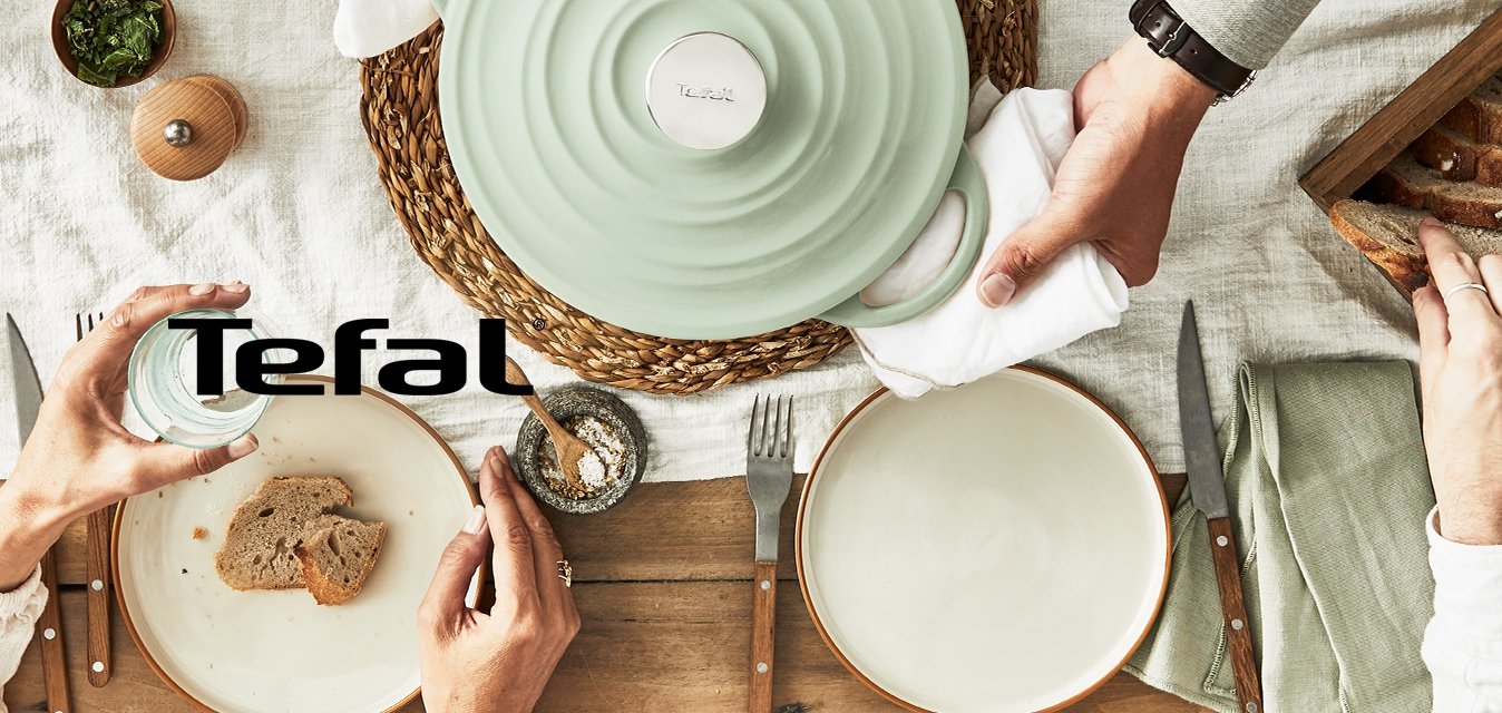 Keramická mísa s mátovým poklopem, žebrovaný design, tkaný ubrus, dřevěná krabice na chléb, plátky chleba, sklenice vody a ozdoby uspořádané na stole.