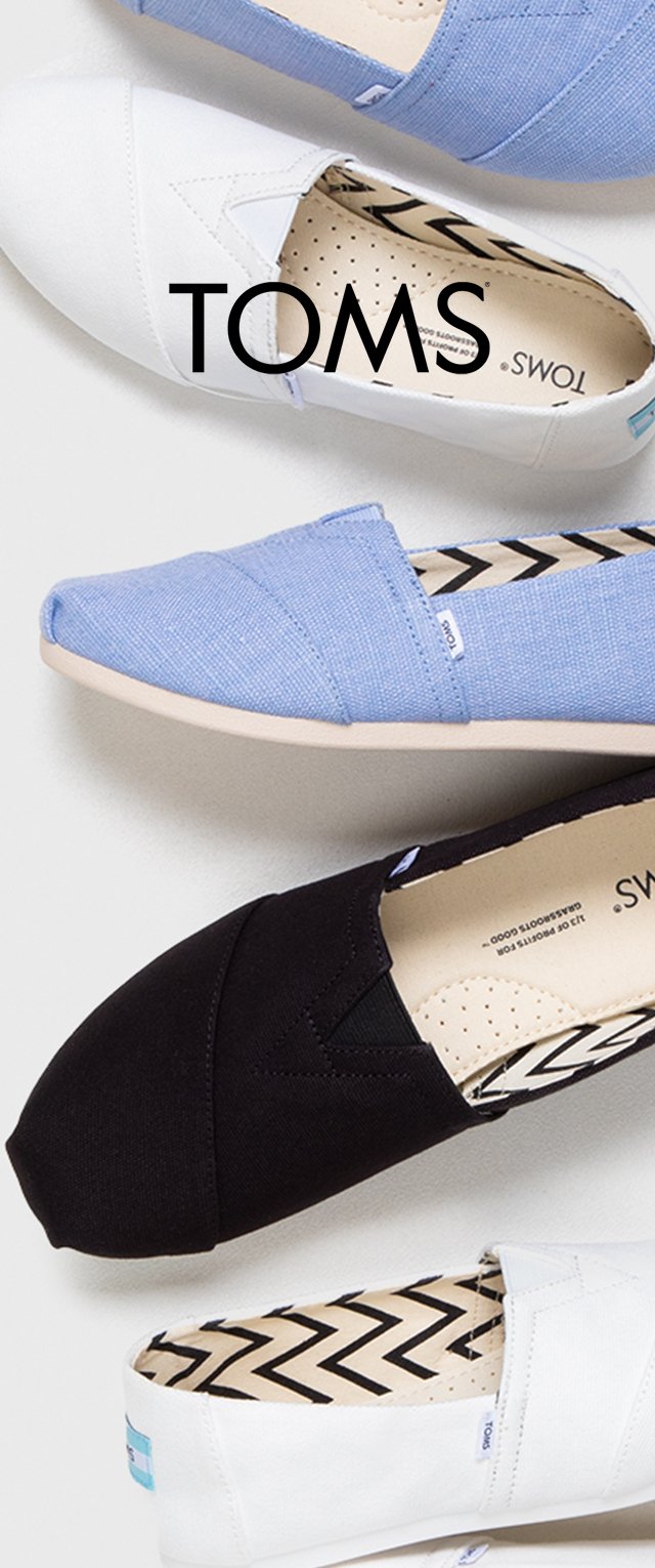 TOMS instappers in zwart, wit en lichtblauw canvas. Ze hebben een ronde neus, een patroon op de inlegzool en een logotag aan de zijkant.
