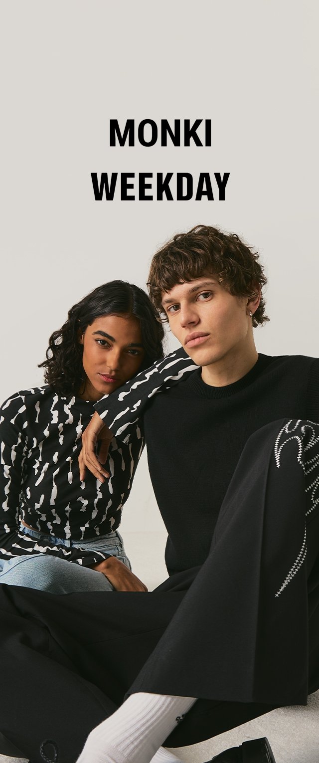 Two models pose seated; woman wears black patterned top and jeans, man wears black sweater and pants with white socks; text "MONKI WEEKDAY" above.