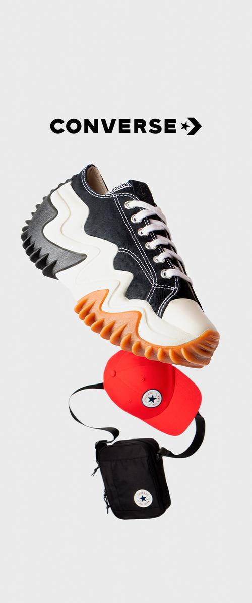 Schwarze Leinensneaker mit weißen Schnürsenkeln, gewellter Gummisohle in Orange und Weiß. Eine rote Tasche mit einem runden Logo sowie eine schwarze rechteckige Tasche sind ebenfalls enthalten.