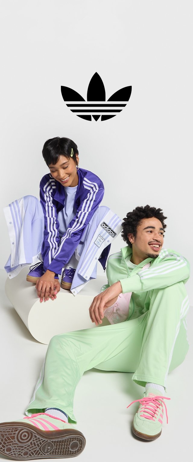 Zwei Models tragen farbenfrohe Adidas Sportbekleidung. Die Frau in Lila und Blau zeigt eine sportliche Jacke und Hose, während der Mann in Mintgrün einen Trainingsanzug mit rosa gestreiften Schuhen kombiniert.